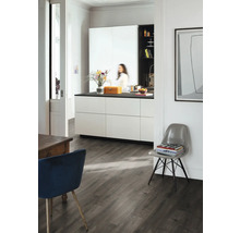 Ljust rum med kök, matbord och stol på mörkt trägolv.