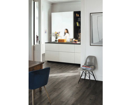 Ljust rum med kök, matbord och stol på mörkt trägolv.