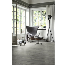 Ljust rum med modern fåtölj, golvlampa och grått vinylgolv med träutseende