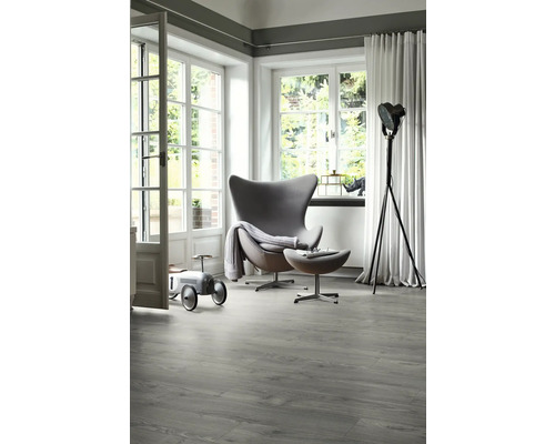 Ljust rum med modern fåtölj, golvlampa och grått vinylgolv med träutseende
