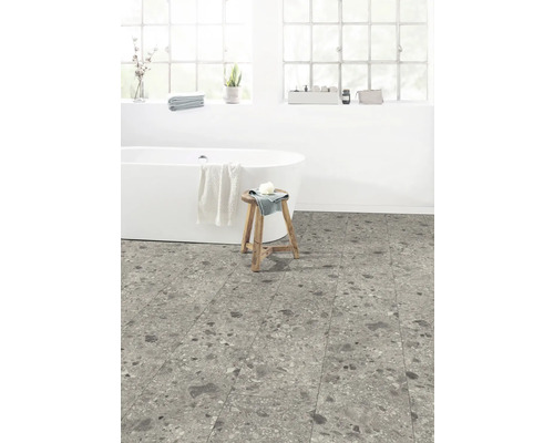 Badrum med fristående badkar, träpall och golvplattor i stenimitation