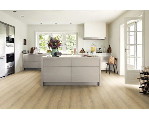 Ljust kök med köksö, köksskåp och trägolv