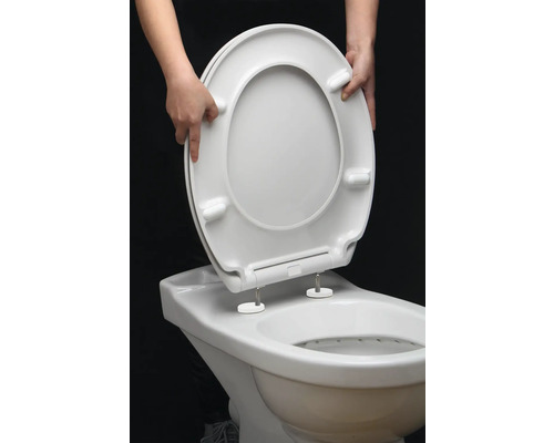 En person monterar en toalettsits på en toalett.
