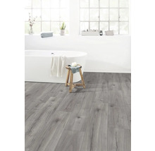 Ljust badrum med badkar, pall och grått laminatgolv.