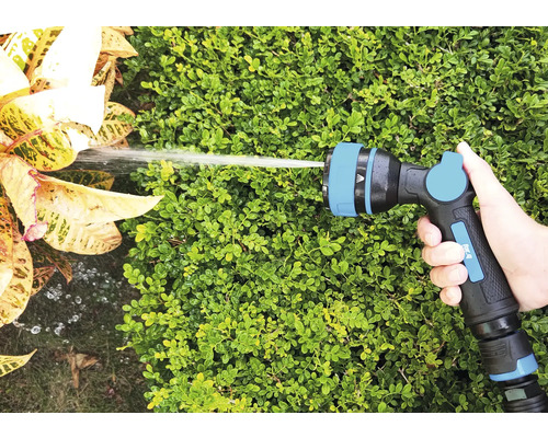 Hand håller trädgårdsslangsprutpistol som vattnar växter