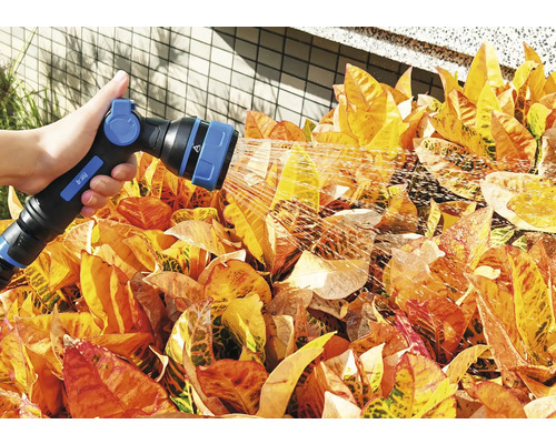 En person vattnar växter med en trädgårdsspruta.