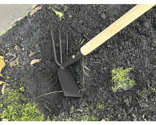 Trädgårdsredskap med träskaft och metallhuvud i jorden