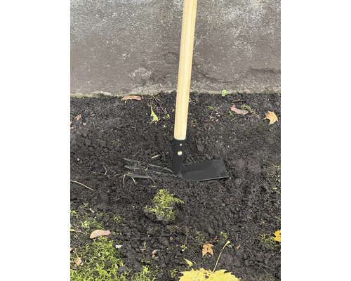 Trädgårdshacka med trähandtag i jorden