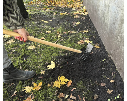 Trädgårdsarbete med en kombinationshacka för jordbearbetning