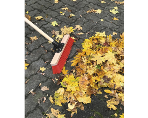 Sop med träskaft och höstlöv på gatstenar