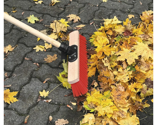 Gatukvast med träskaft och höstlöv på gatstenar