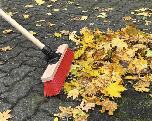 Kvast sopar ihop höstlöv på gatsten