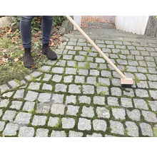 Person som rengör stenläggning med fogborste