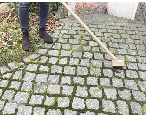 Person som rengör stenläggning med fogborste