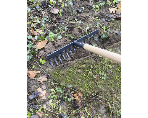 Trädgårdsräfsa med trähandtag vid utjämning av mark