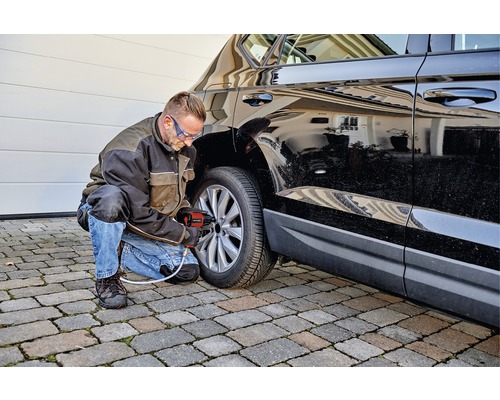 Man byter ett däck med en pneumatisk mutterdragare på en svart bil