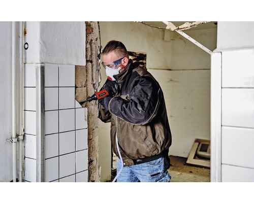 Hantverkare tar bort kakel med en bilningshammare i ett rum.