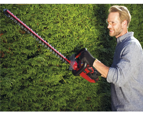 Man klipper häck med en häcksax