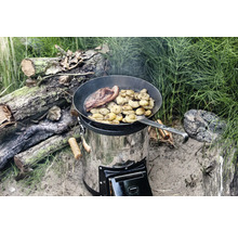 Vedeldad spis av rostfritt stål med stekpanna där mat tillagas