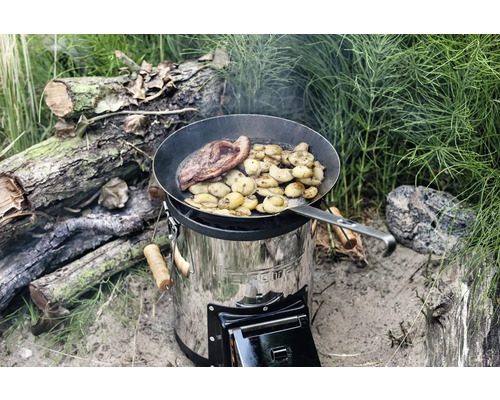 Vedeldad spis av rostfritt stål med stekpanna där mat tillagas