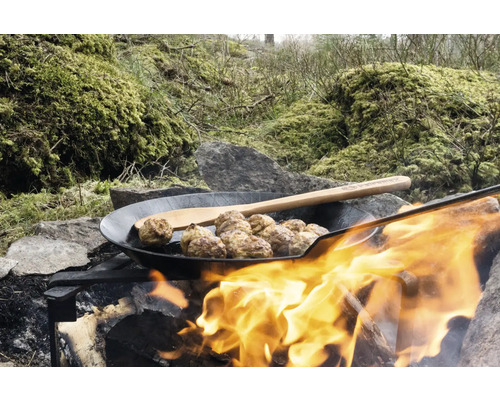 Köttbullar i en panna över en lägereld med en träslev