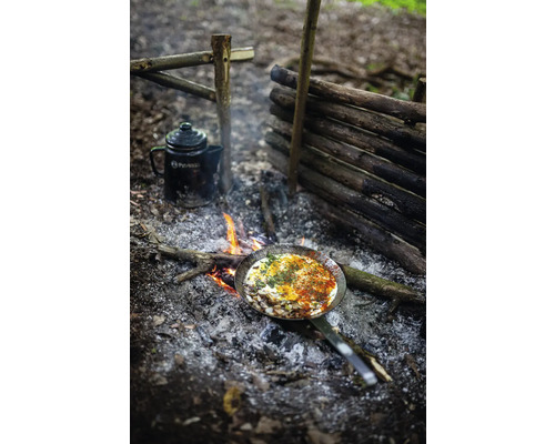 Utomhusscen med lägereld, stekpanna med mat och en kanna.