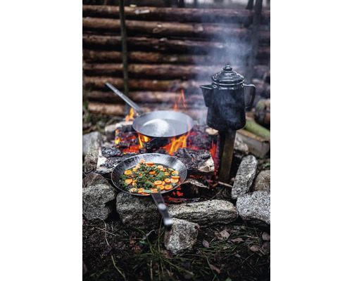 Matlagning utomhus med två stekpannor och en kaffekanna över öppen eld.