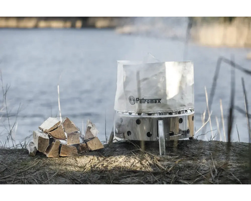 Petromax eldkorg med vedstapel vid sjöstranden