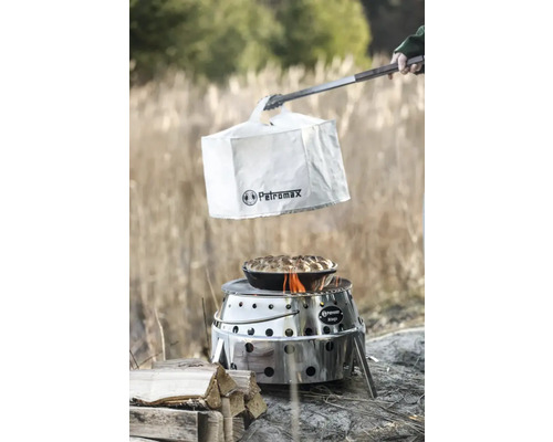 Petromax Atago grill med skyddshuv, tång och tillagad maträtt utomhus