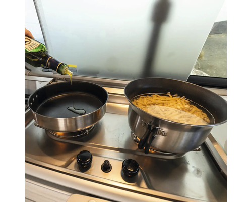 Två kastruller på en spis, i en kastrull kokar pasta, i den andra hälls olja.