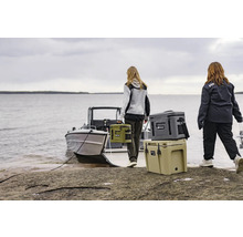 Scen med två personer som bär kylväskor till en båt på stranden