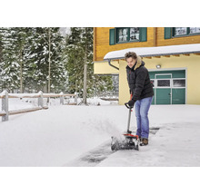 Man röjer snö framför ett hus med en snöslunga