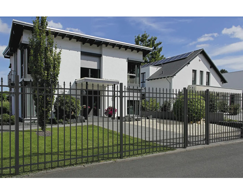 Metallstaket framför ett bostadshus med gräsmatta