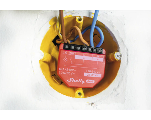 Detaljbild av ett Shelly Gen3-relä i en gul infälld dosa med elektriska ledningar.