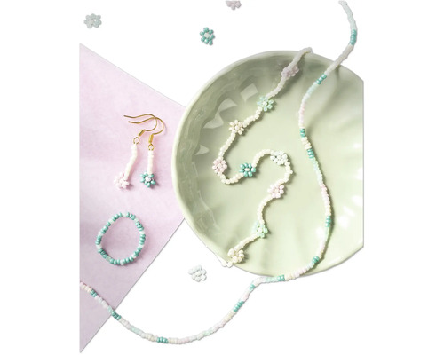 Pärlsmyckeset med halsband, ring och örhängen i en ljusgrön skål