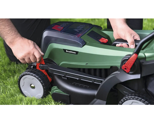 Översikt över en person som använder en sladdlös gräsklippare på en gräsmatta