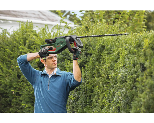Man klipper häck med batteridriven häcksax
