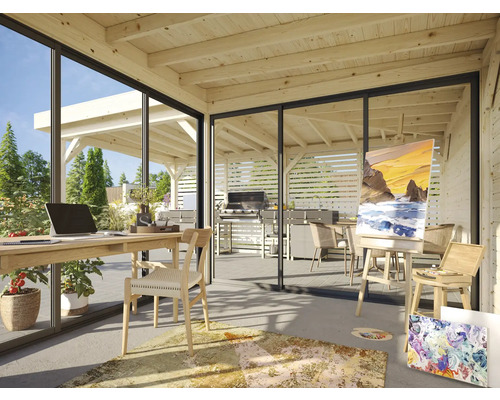 Ljust rum med trätak, skrivbord, stol, staffli och utsikt över trädgården med grillplats