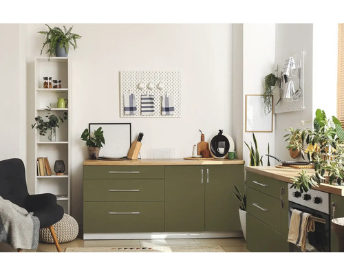 Ljust kök med gröna skåp, träbänkskivor och diverse dekorativa föremål