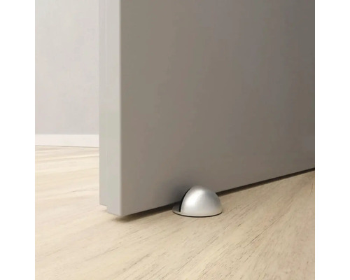 Dörrstopp i metall på golvet framför en dörr