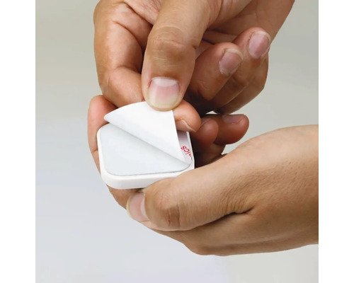 Händer tar bort skyddsfilmen från en självhäftande pad