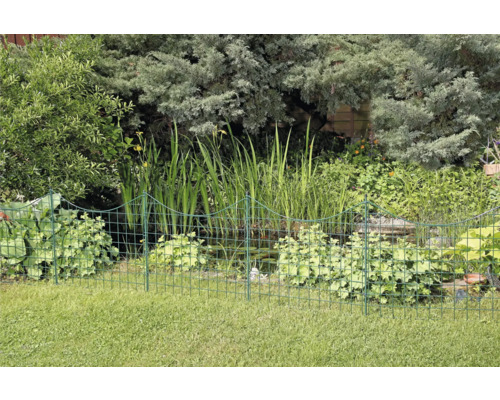 Trädgård med damm och lågt metallstaket