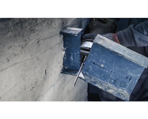 En byggnadsarbetare skär en metallprofil med en skärmaskin.