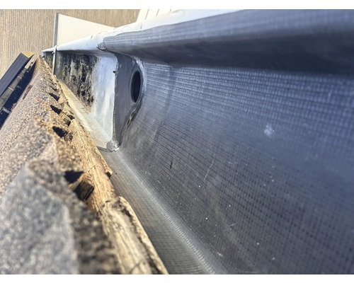 Detaljvy av en takränna med bitumen tätning och avloppsrör