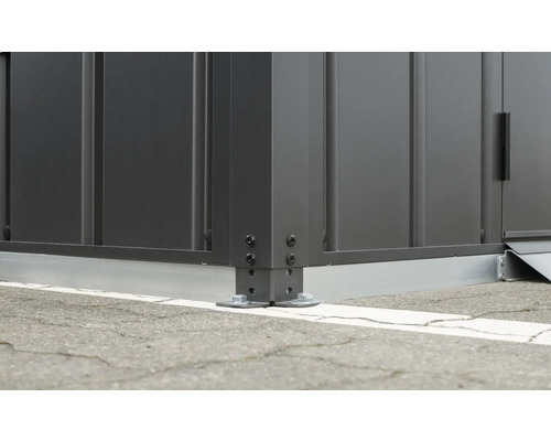 Detaljvy av ett hörn av ett trädgårdsskjul med skruvinfästning i marken.