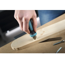 En hand sänker en försänkare av märket Wolfcraft i en träplanka för att försänka en skruv.