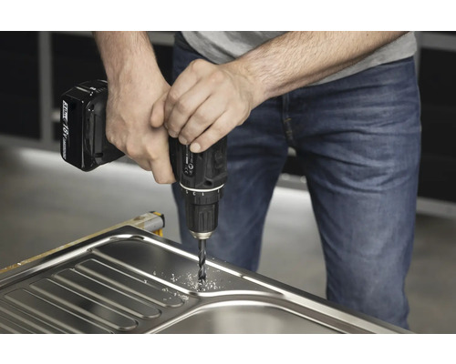 Hantverkare borrar ett hål i en diskho med en borrmaskin