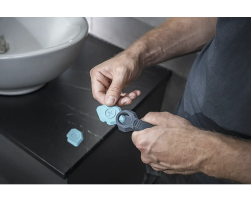 Man använder ett fogverktyg i badrummet för silikonfogar.