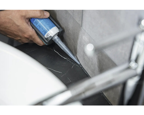 En person applicerar silikon på en marmoryta.