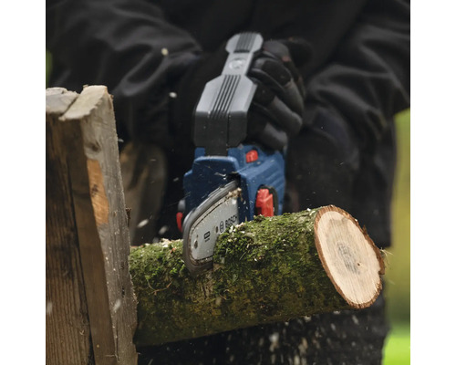 Person sågar vedträ med en Bosch batteridriven motorsåg